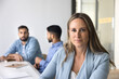 © fizkes - Confident professional. Portrait beautiful middle aged businesswoman international company worker employee posing at meeting table in modern office looking at camera taking break in collaborative work