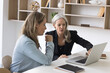 © fizkes - Professional consultation. Experienced senior businesswoman bank manager financial advisor meet with female client customer in work office give advice support explain contract details using notebook