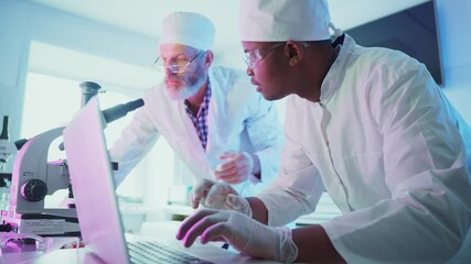 Wall Mural - two professional scientists wearing lab coats, bouffant caps, and safety glasses, collaborate on res
