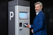 © zinkevych - Man paying parking fee using card at automatic machine