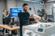 © standret - White printed object in hands. People are in the office by the 3d printer