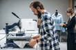 © standret - Guy in checkered shirt is working. People are by the sewing machines indoors