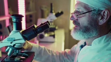 Wall Mural - professional scientist wearing white lab coat and surgical cap carefully adjusting laboratory micros