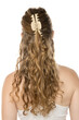 © vladimirfloyd - Back view of young woman with long wavy blonde hair partially secured with beige claw clip, showing half-up hairstyle against white background