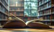 © john - Close-up of an open book on a wooden table in a library with blurred bookshelves in the background