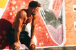 © djile - Muscular athlete resting after intense workout against graffiti wall