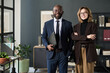 © pressmaster - Portrait of multiethnic business couple smiling at camera while standing in office
