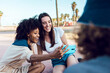 © Xavier Lorenzo - women friends taking a selfie with smart phone outdoors - Joyful multiethnic female couple having fun with their friends in summer holidays. Millennial generation, friendship and youth concept