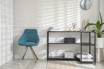 Poster - Console table with different decor and chair near white wall indoors. Interior design