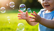 © ShaNeT - Toddler hands reaching for iridescent soap bubbles over green grass