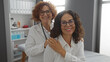 © Krakenimages.com - Two mature hispanic women, a doctor and patient, smiling in a hospital clinic room, conveying a sense of friendly healthcare interaction and supportive medical care.