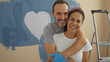 © Krakenimages.com - Middle-aged hispanic couple painting their new home with a heart on the wall, expressing love and happiness indoors.
