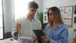 © Krakenimages.com - Man and woman discussing business strategy in a modern office setting with documents and a digital tablet.