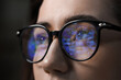 © New Africa - Young woman wearing glasses with reflection on dark background, closeup