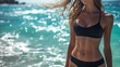 © Iurii - Athletic woman showcasing abs and obliques at ocean edge on sunny day