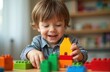 © Pete - Happy toddler boy builds colorful blocks in playroom. Child plays with building toy blocks creating house. Preschool learning activity at home. Education concept, childhood fun.