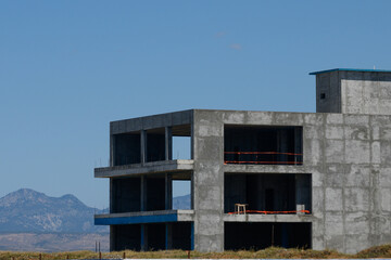 construction of a modern building structure against a clear blue sky and mountain backdrop in late a