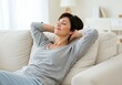© Selda - A relaxed woman rests on a couch, enjoying a moment of peace and tranquility indoors with a smile.