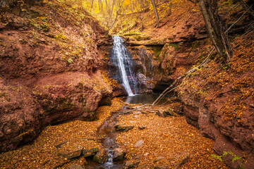 Aufkleber - A magical view of a waterfall in the middle of an autumn forest in a narrow gorge. Rusyliv Falls, Ukraine, Europe.
