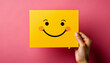 © anandart - smiley note, yellow paper, pink background, emotional wellness, yellow day, cheerful message, minimal design, hand holding note, happiness symbol, uplifting paper, mental health, color therapy, joyful