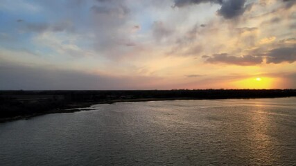 Wall Mural - drone aerial flying above a small lake at sunset with colorful sky reflecting in water with small wa