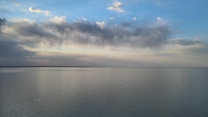 Wall Mural - drone flying slowly above a large calm lake that is reflecting the pastel colors from the sky. small