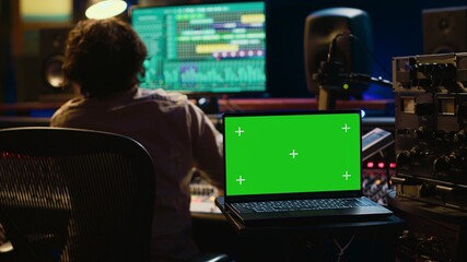 Leinwandbilder - Artist and sound designer working as a team to produce new tracks, greenscreen laptop. Musician and audio technician collaborating on music, mixing on audio console with motorized faders. Camera A.