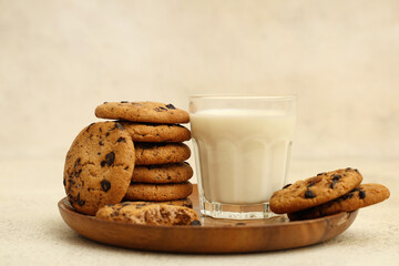 Wall Mural - wooden plate of sweet cookies with chocolate chips and glass of milk on white background