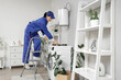 © Pixel-Shot - Female worker with stepladder and tools near modern electric boiler in bathroom
