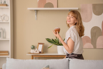 Wall Mural - young woman with tasty muffin at home