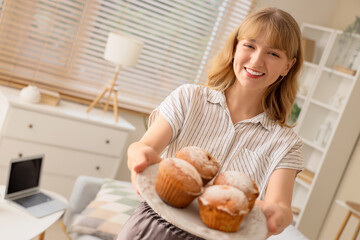 Wall Mural - young woman with tasty muffins at home