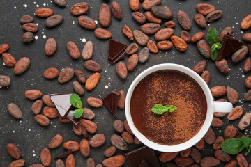 Wall Mural - cup of hot chocolate with mint leaves and cocoa beans on black grunge background