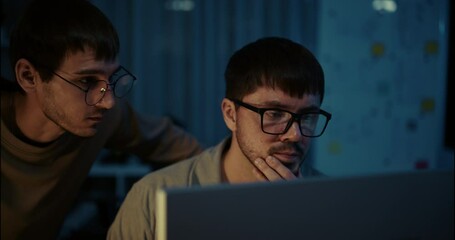 Team of young programmers focused on coding at night. Collaboration, problem solving, and teamwork in modern tech environment.