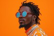 © Georgii - Stylish man wearing vibrant clothing with reflective sunglasses on orange background