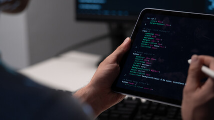 software engineer is coding on tablet, using stylus to write and edit code. screen displays colorful syntax highlighting, indicating active development. coding developer software engineer