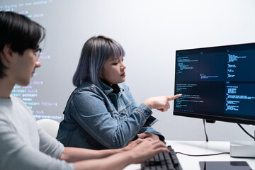 two software developers are collaborating coding project, with one pointing computer screen displayi