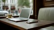 © VK Studio - A cozy café scene with a laptop and smartphone on a wooden table, inviting productivity amidst urban hustle visible through the blurred background window.