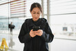 © zhouyilu - Young Woman Engaged in Mobile Communication at Airport Terminal