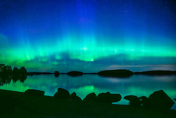 Wall Mural - northern lights dancing over calm lake in farnebofjarden national park in north of sweden
