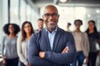 © Vorda Berge - Portrait of a smiling mature businessman posing in front of her coworkers in modern office