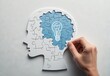 © Hurgan - Puzzle head with lightbulb, representing  innovation and problem-solving.  A hand completes the jigsaw puzzle, symbolizing the process of finding the solution