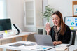 © PaeGAG - Smiling businesswoman waving during video call in office