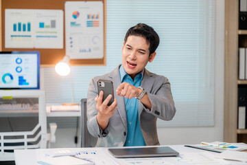 Poster - Asian businessman having video call and pointing finger at smartphone in office