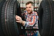 © Serhii - Tire repair service. A man chooses new tires for his car.