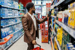 © Dusan Petkovic - Side view of interracial man standing at supermarket and choosing bottle of juice.