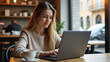 © Konstantin - Young woman working on a laptop in a coffee shop