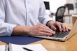 © New Africa - Man working on laptop at wooden desk in office, closeup