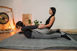 © phoenix021 - Masseuse performing Thai yoga massage on a woman pulling her by the both hands stretching her back