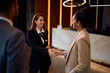 © Drazen - Happy female concierge greeting a business couple in hotel lobby.