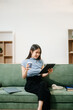 © Nuttapong punna - Young Asian woman listening music from headphones and writing note for her work idea in diary book.She in home